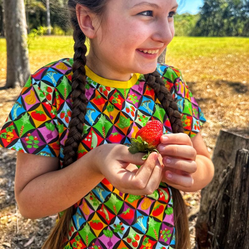 Young girl with braided hair wearing a colorful shirt in a natural setting