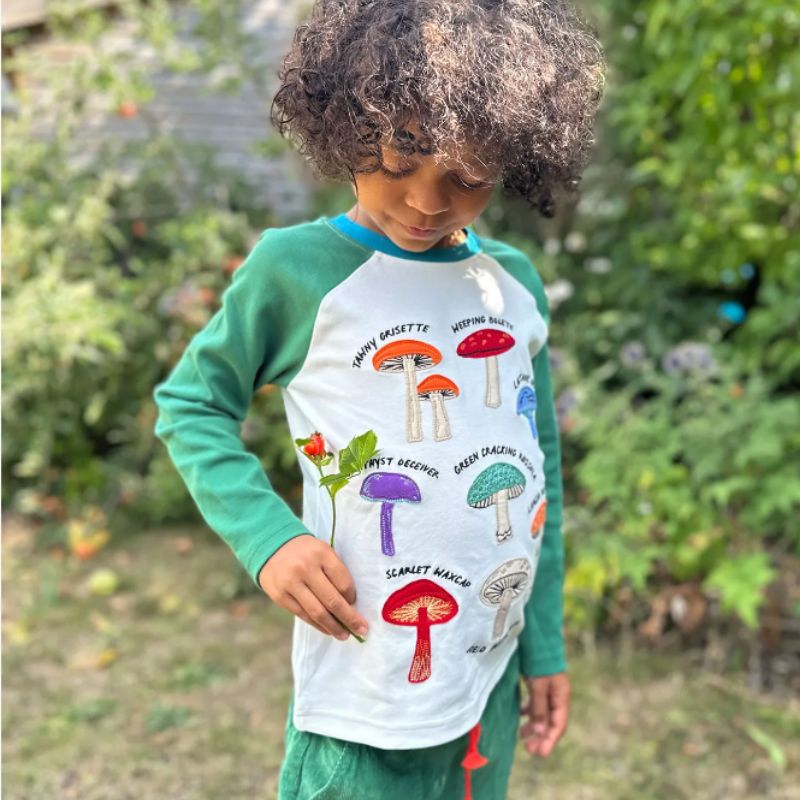 Child wearing a shirt with colorful mushroom designs outdoors
