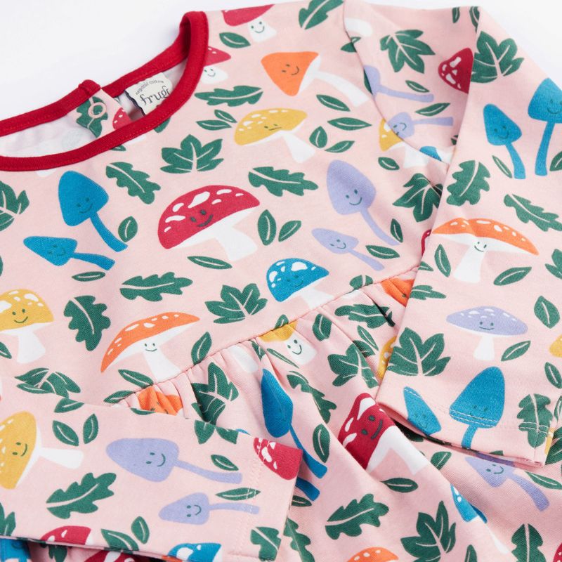Children&#39;s dress with colorful mushroom and leaf pattern on a pink background