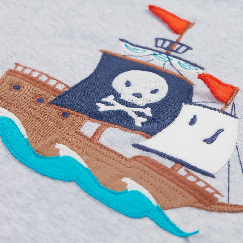 Embroidered design of a pirate ship with a skull and crossbones flag on a textured fabric background.