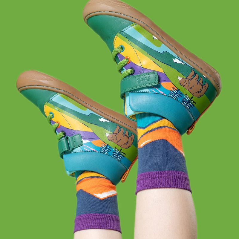 Colorful children&#39;s sandals and socks on a green background