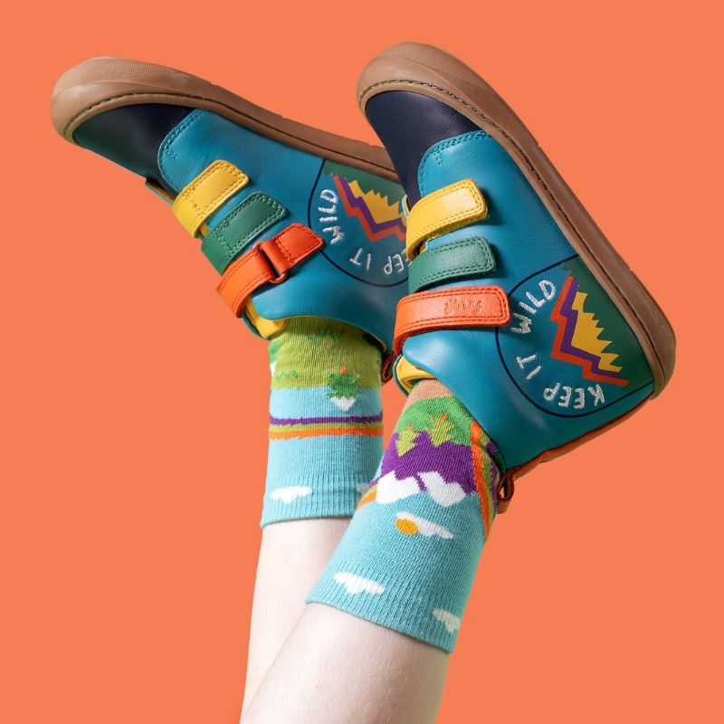 Colorful children&#39;s shoes and socks with a brand logo on an orange background