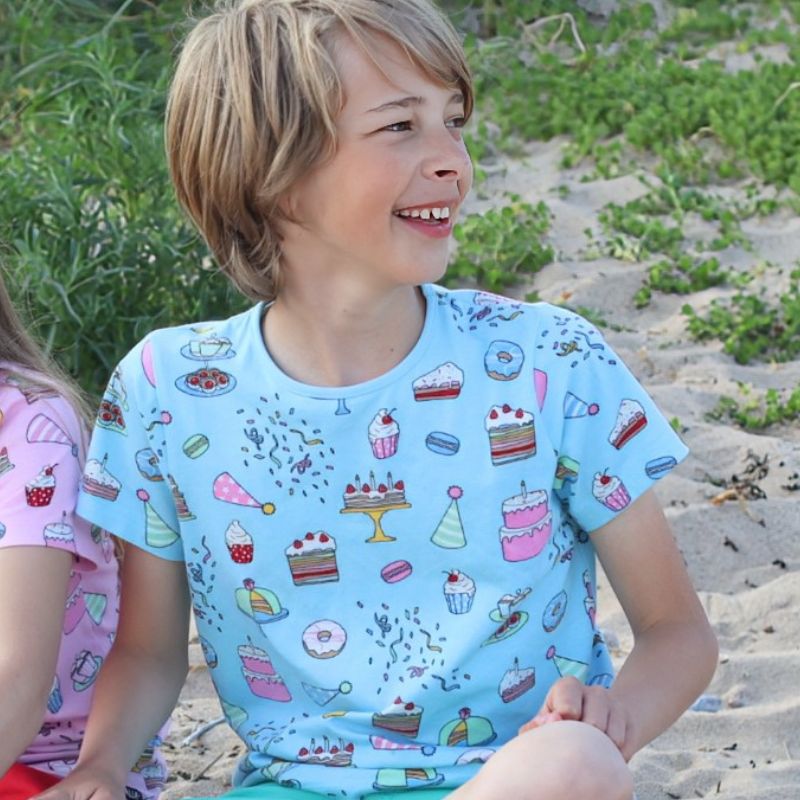 Child wearing a blue t-shirt with cake pattern on a beach