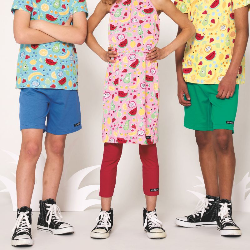 Three children wearing colorful outfits with patterned shirts and shorts on a white background