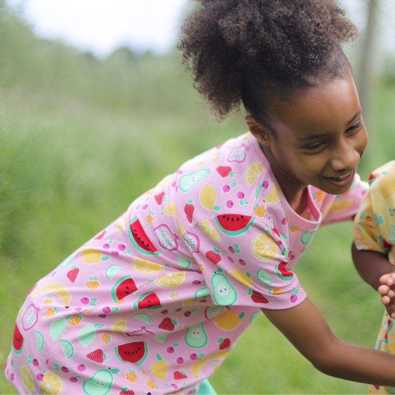 Child wearing a pink shirt with colorful fruit patterns outdoors
