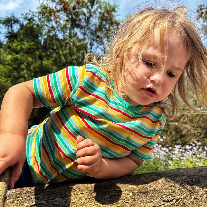 Child wearing a colorful Villervalla striped shirt outdoors
